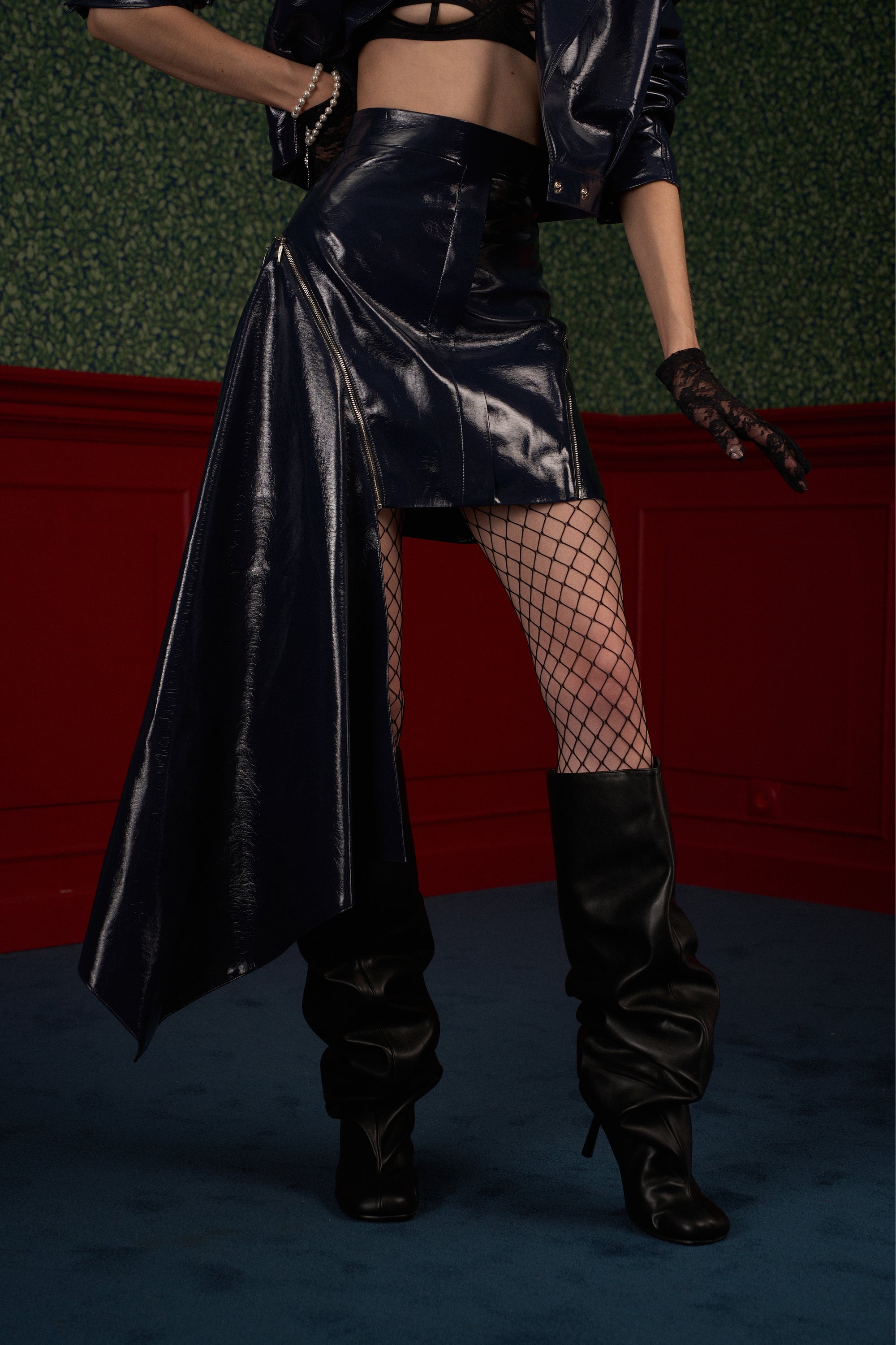 Side profile of model in navy asymmetric vegan leather skirt showing panel drape.