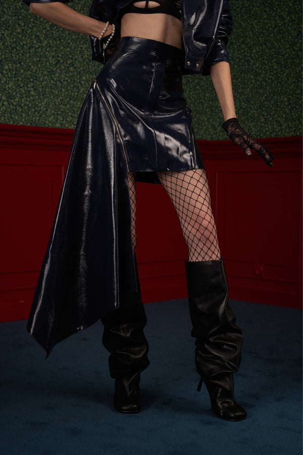 Side profile of model in navy asymmetric vegan leather skirt showing panel drape.