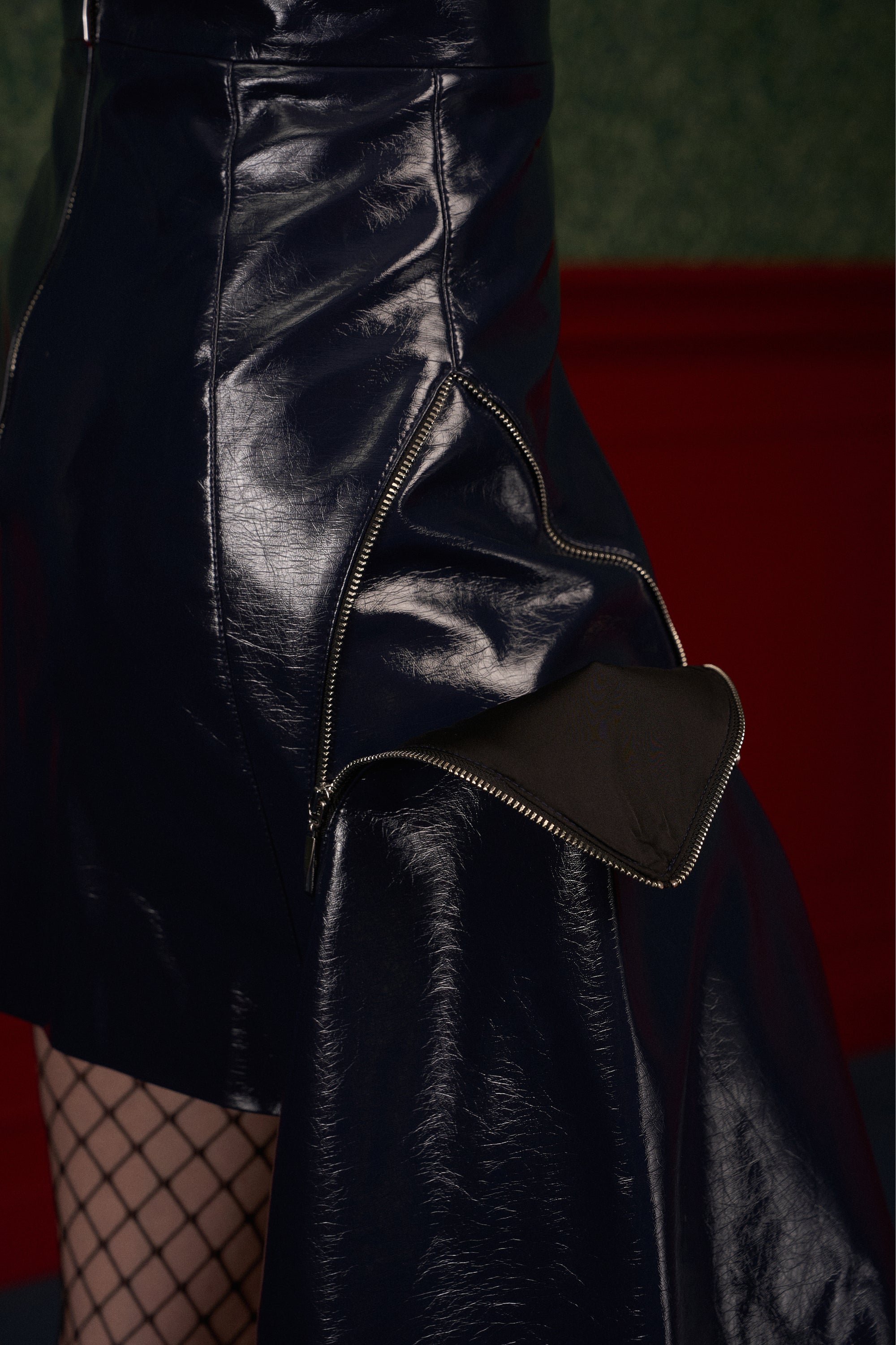 Close-up of the metal zipper that detaches the removable panel on the "The Weapon" navy asymmetric vegan leather skirt